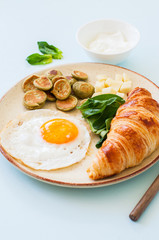 Healthy breakfast, fried eggs with spinach pancake cereals cheese and croissant in a plate.