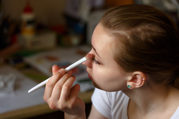 Portrait of a girl doing make up with a white brush view from above