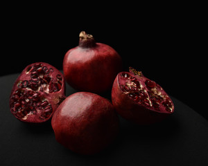 close up of a fruit still life, pomegranates cut open on a black studio background.