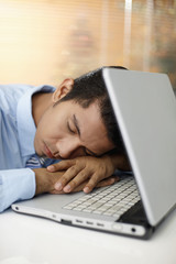 Young businessman sleeping on laptop