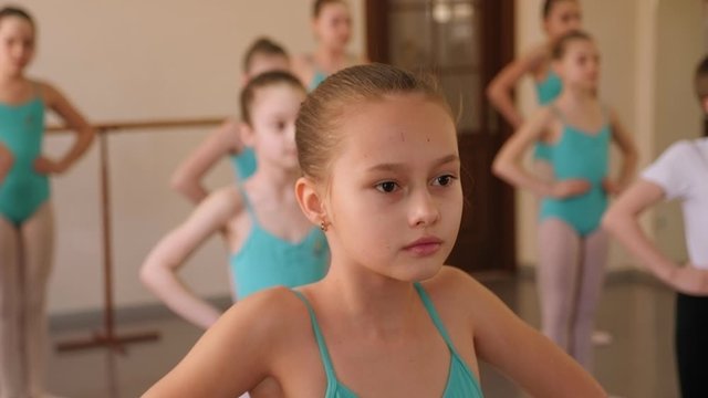 Young dancers warming up at ballet class. Close-up of little girls and one boy warming up before a ballet lesson at a ballet school.