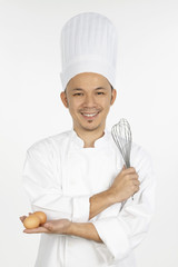 Asian chef with whisk and eggs in each hand