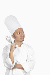 Asian chef with whisk, deep in thought