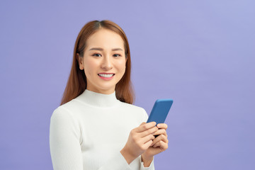 Portrait of a happy young girl holding mobile phone isolated