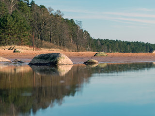 Obraz premium seascape on a sunny spring day, sandy sea shore, rocks on the shore
