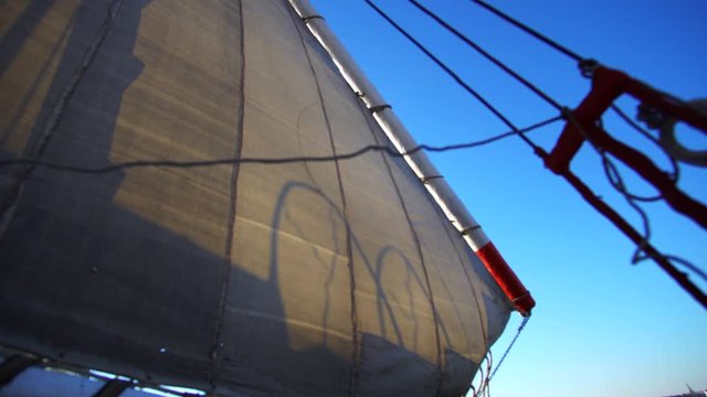 Felucca boat in Egypt local Egyptian navigator shadow over white sail while cruising the Nile river