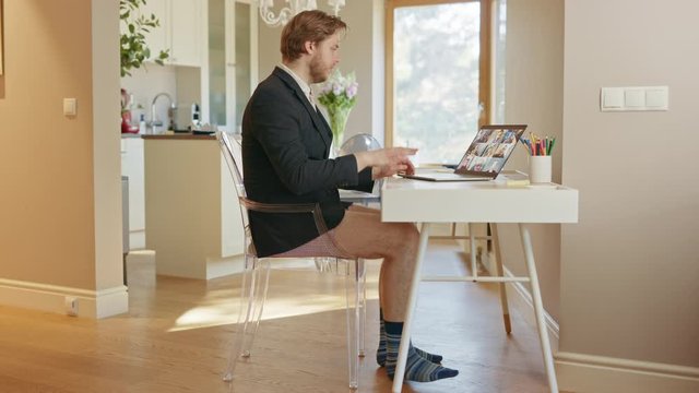 Funny Clip: Businessman Wearing Jacket and No Pants Uses Laptop and Conference Video Call Software App for Board of Directors Online Meeting. Remote Work, Work at Home, Home Office Concept. Side View