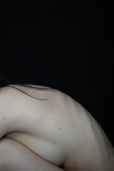 Nude figure of a young woman on a black background. Curved back with ribs. Skin. The curves of the body. The curve of the back. The art of the naked body. Beautiful figure. Slim.