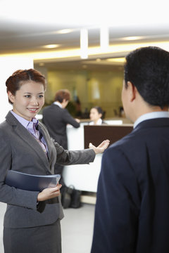 Sales Representative Of Car Dealership Ushering Customer To The Counter