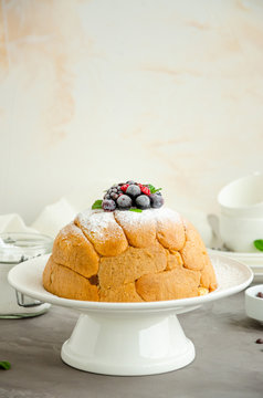Traditional Italian cake Zuccotto on a white plate decorated with powdered sugar and berries on top. Vertical orientation. Copy space, selective focus.