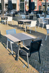 Empty terrace of a closed restaurant in The Netherlands with plenty of space between tables and chairs during coronavirus restrictions waiting to reopen. Social distancing concept. Vertical image.