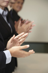 Obraz premium Business people standing in a row, clapping their hands