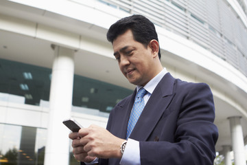 Fototapeta premium Businessman text messaging on smart phone