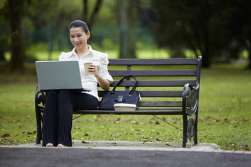 Fototapeta premium Mid adult businesswoman working in the park during coffee break