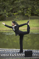 Mid adult businesswoman in yoga pose at the park
