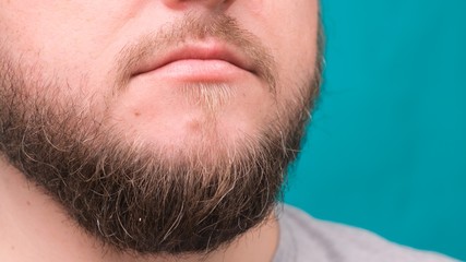 Obraz premium Close-up of male lips and bearded chin on a green background