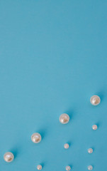 White beads lie in a row on a blue background. Needlework and embroidery. Background and texture.