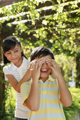 Girl covering boy's eyes with her hands
