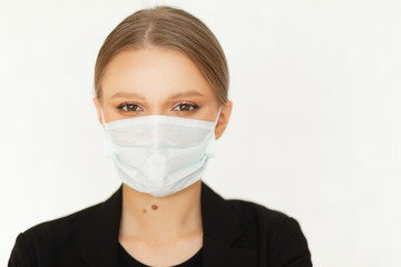 A woman businessman in a suit has put on a mask for protection against a virus at work and is looking at the camera.