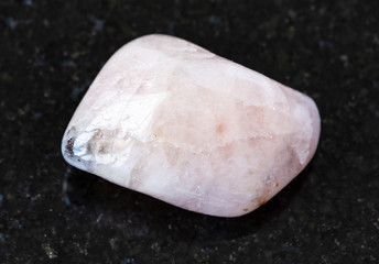 closeup of sample of natural mineral from geological collection - polished Morganite (Vorobyevite, pink Beryl) rock on black granite background from Mozambique