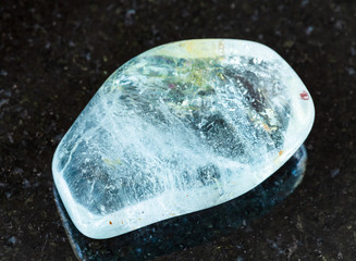 closeup of sample of natural mineral from geological collection - tumbled blue Topaz rock on black...