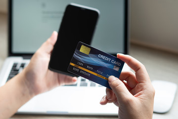 Business woman hand hold credit card to shopping internet online bill on computer, Debit saving purchase buy on table background. Shopaholic people retail pay sale money, bank terminal account concept
