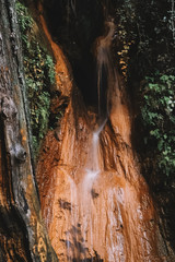Fototapeta na wymiar waterfall over mountain. natural mineral water spring that oxidizes the ground, from. there is its characteristic brown color. no people
