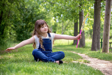 Naklejka na ściany i meble Happy child girl with colorful pinwheel windmill in summer