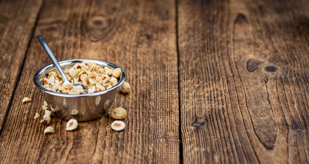 Freshly chopped Hazelnuts on an old wooden table (close up; selective focus)