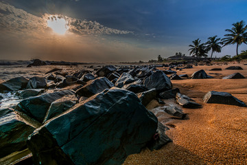 Beach with red sand and black rocks with a beautiful sunset in Congo Town, Monrovia, Liberia - obrazy, fototapety, plakaty