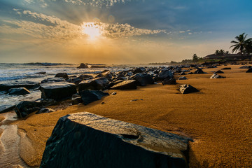 Beach with red sand and black rocks with a beautiful sundset in Congo Town, Monrovia, Liberia - obrazy, fototapety, plakaty