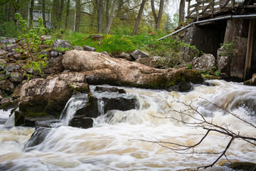 Turbulent river rapids under an old wooden bridge in Scania, southern Sweden.