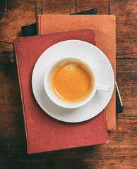 Vintage books and a cup of coffee on wooden background