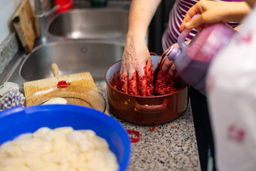 Manos de mujer vertiendo sangre de cerdo sobre la mezcla de relleno de morcillas tradicionales de arroz de Burgos. Tomada el 20 de febrero de 2020 en Burgos, Castilla y León.