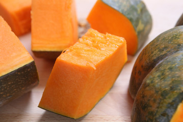 yellow pumpkin cut into pieces on wooden table