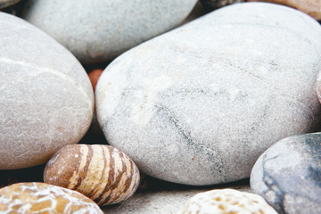 Fototapeta na wymiar Mix of rounded multicolor textured stones on sea beach . Close up coast shoot