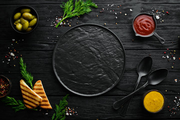 The background of cooking. A set of spices and fresh vegetables. Top view. Free space for your text. On a black stone background.