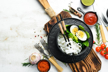 Rice noodles with egg, broccoli and spinach. Asian cuisine. Top view. Free space for your text.