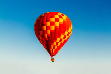Bright red-yellow hot air balloon against a blue sky
