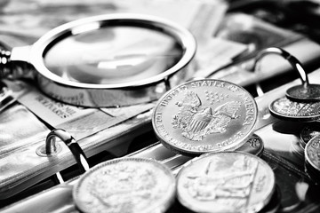 Silver dollar and numismatic coins with magnifying glass