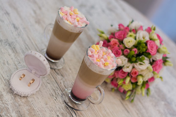 Wedding bouquet of roses on a table with wedding rings and coffee
