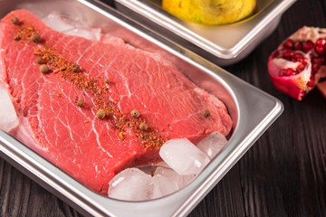 fresh meat with spices in ice on dark background 