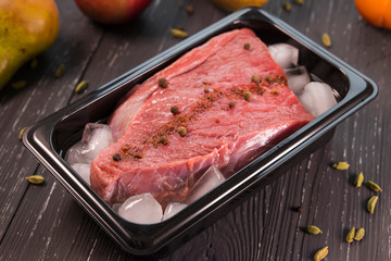 fresh meat with spices in ice on dark background 