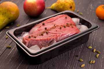 fresh meat with spices in ice on dark background 