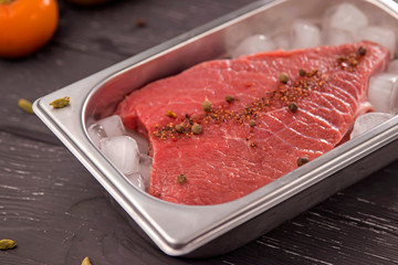 fresh meat with spices in ice on dark background 