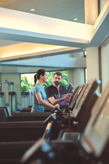 Personal trainer working with client in gym. Trainer man helping woman with her work out