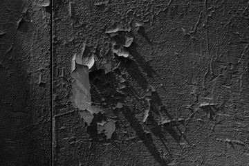 Black paint peels off an old metal surface. Shot on a black and white film. Grunge pattern.