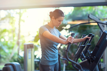 Fototapeta na wymiar Woman exercising at the gym in an elliptical trainer. Young woman doing cardio training