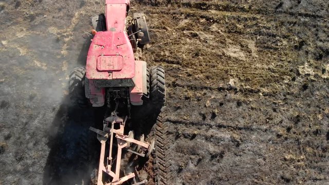 Top view of a tractor with a reversible plow that plows heavy ground. Agronomic activity on farmland, the concept of agribusiness