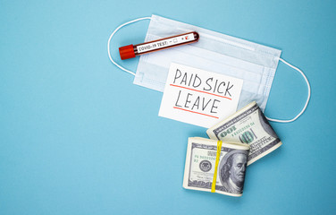 paid sick leave with a medical mask and money on a blue background. dollars in a pack and a positive test for covid-19